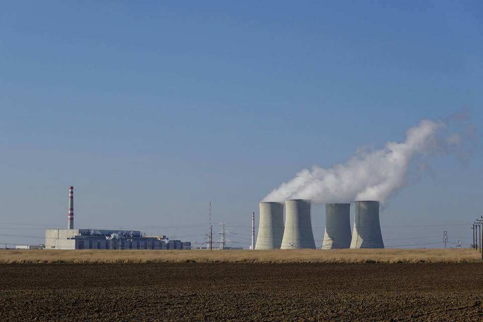 Power plant cooling towers releasing steam under a clear sky